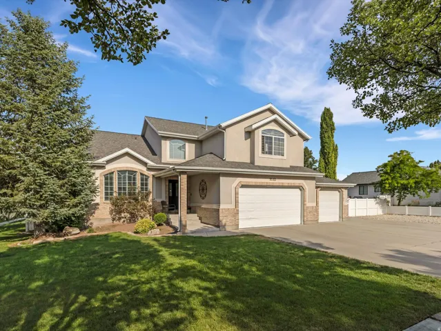 Stucco and stone facade home featuring a covered entry, arched windows, and an attached two-car garage with an additional single-car garage