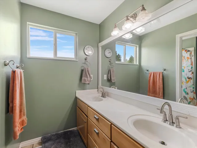 Bathroom featuring a dual-sink vanity with light wood cabinetry and brushed nickel hardware