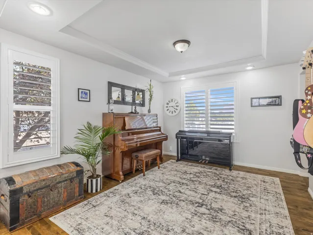 Interior room featuring wood-finish flooring, white walls, and a tray ceiling with recessed lighting