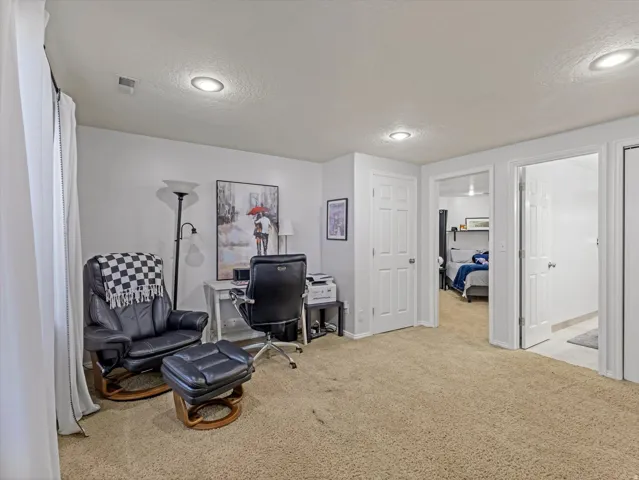 Carpeted room with recessed lighting and white walls, featuring multiple white interior doors