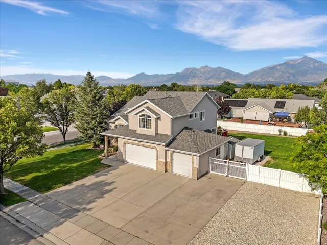 Two-story property featuring a stucco and stone exterior, multi-car garage, and a lush green lawn