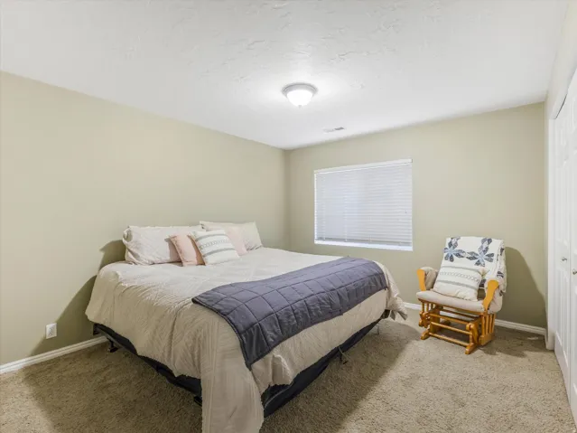 Bedroom featuring neutral wall paint, textured carpet, and a window with blinds