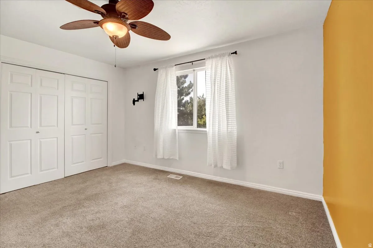 Primary bedroom carpeted interior space featuring a ceiling fan with integrated lighting