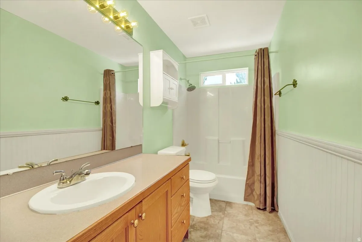 Bathroom featuring a wood-finish vanity with an integrated sink, a large wall mirror, and a full bathtub with shower