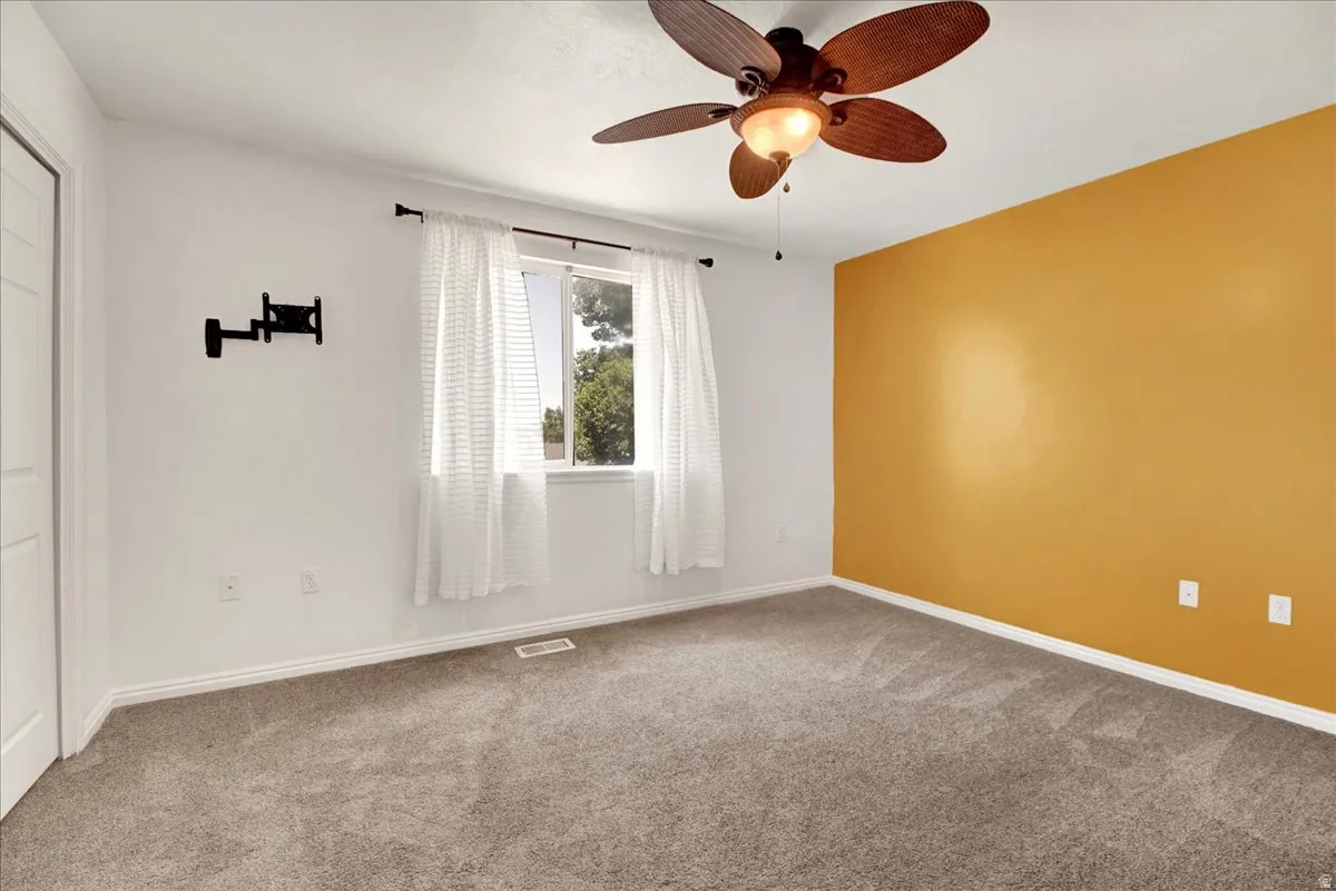 Primary bedroom with neutral carpeting and a warm accent wall