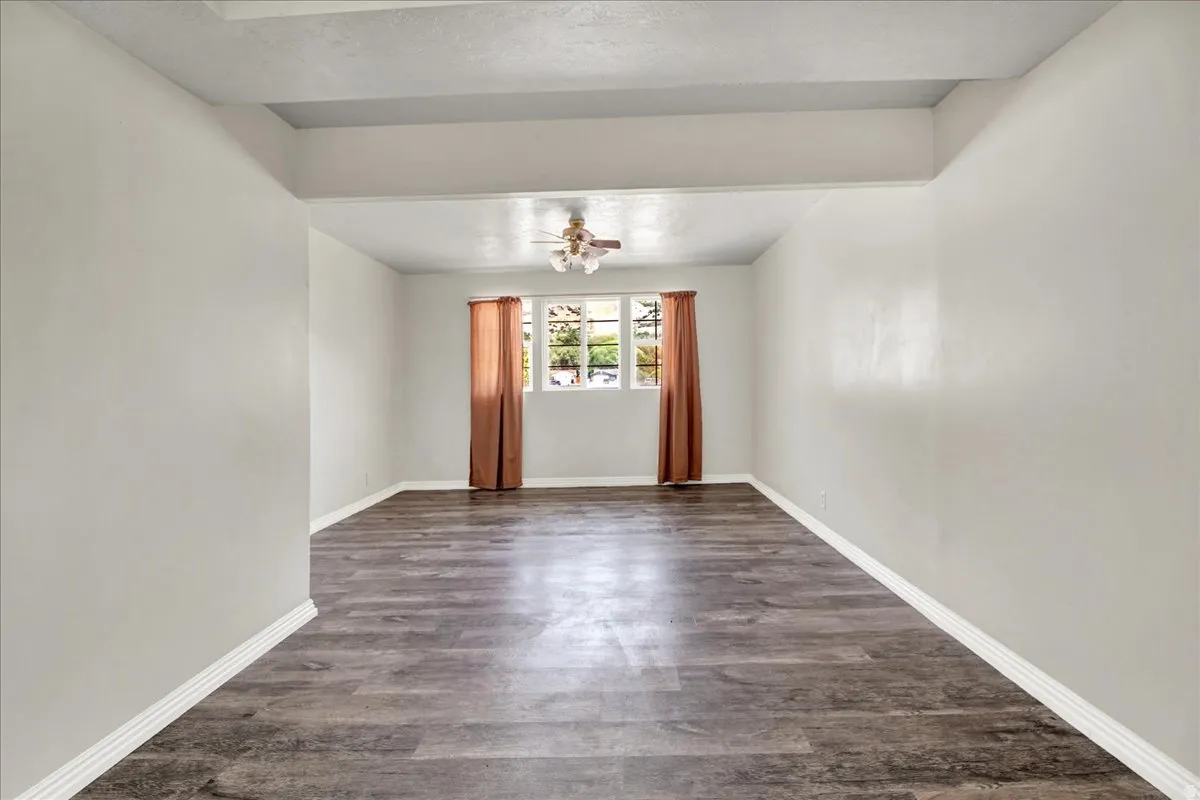 Spacious room featuring wood-finish flooring, white baseboards, and a window with natural light