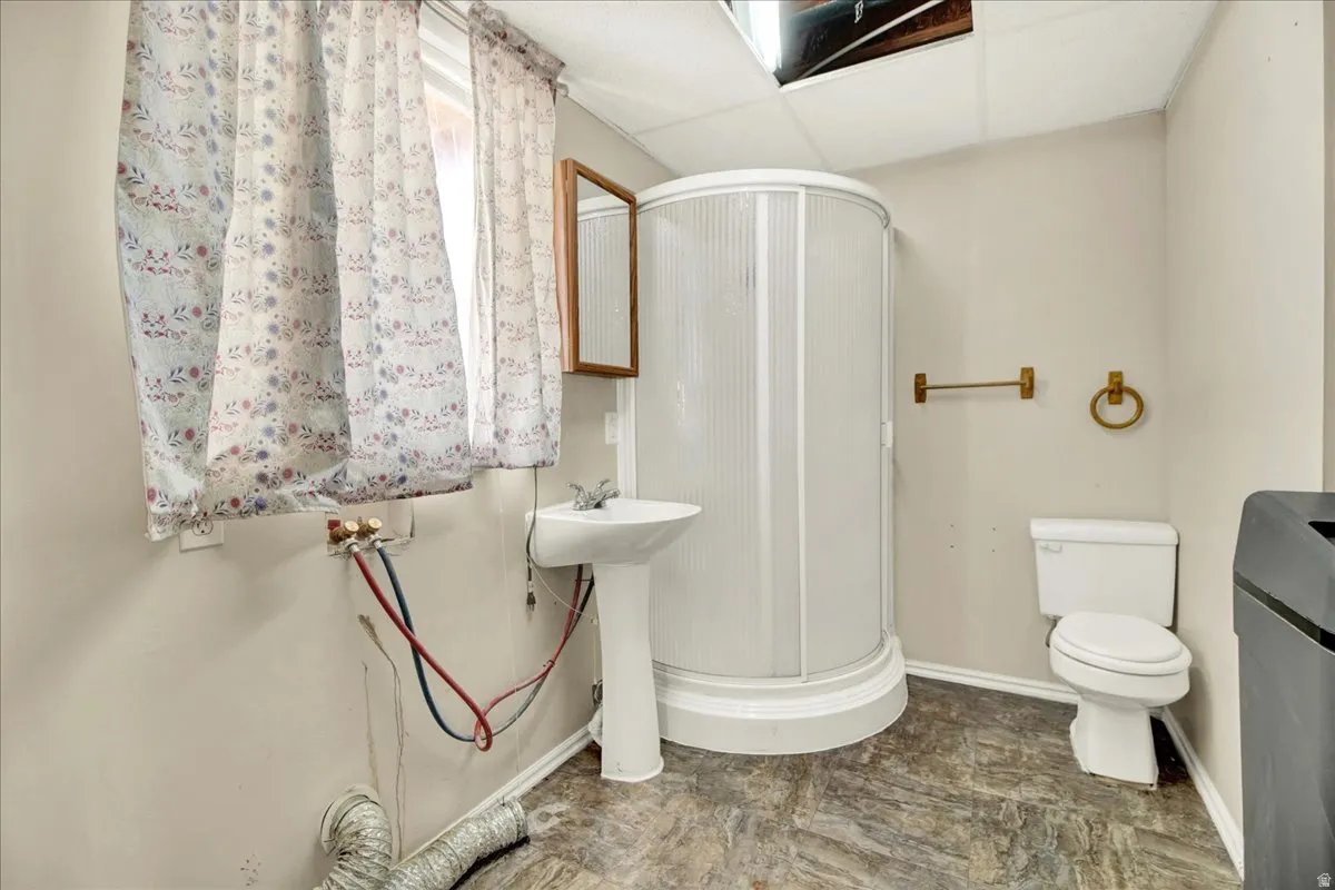Laundry, 3/4 bathroom featuring a stand-alone shower unit, pedestal sink, and toilet