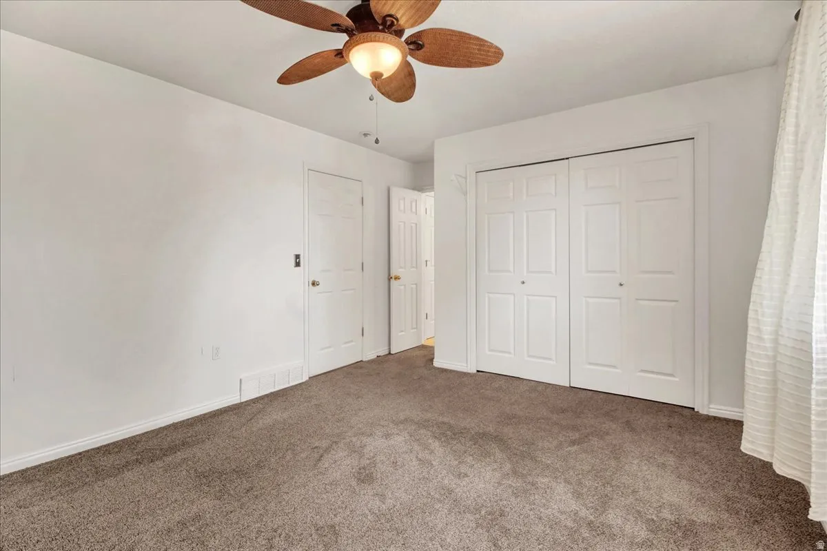 Primary bedroom neutral-toned wall-to-wall carpeting complements the white walls