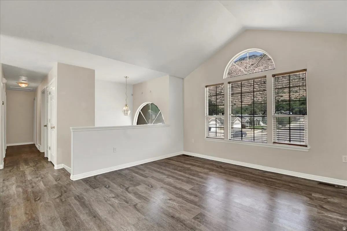 Vaulted ceiling living space featuring wood-finish flooring