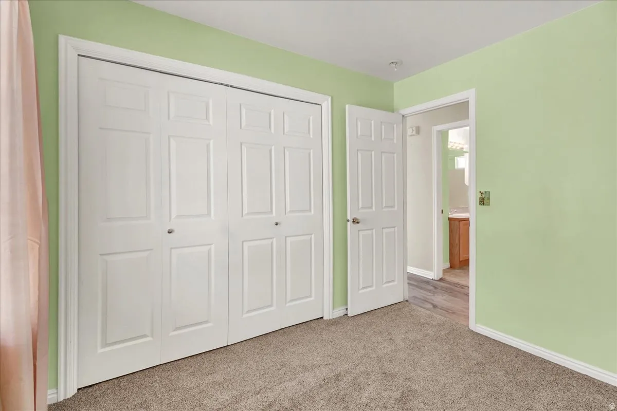 Room featuring broadloom carpet, light green wall paint, and white baseboards