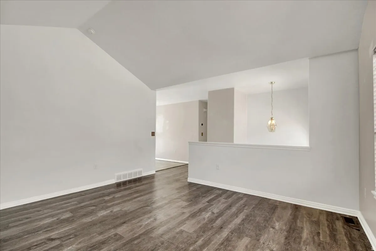Interior living space featuring wood-finish flooring, vaulted ceiling, and a prominent half-wall architectural element