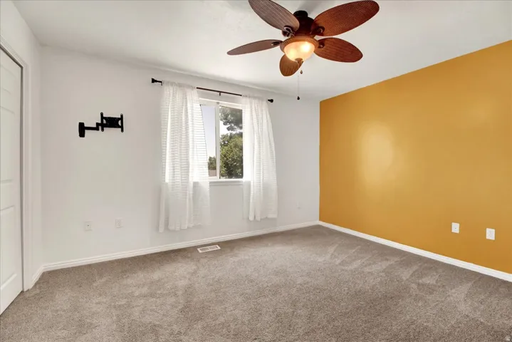 Primary bedroom with neutral carpeting and a warm accent wall