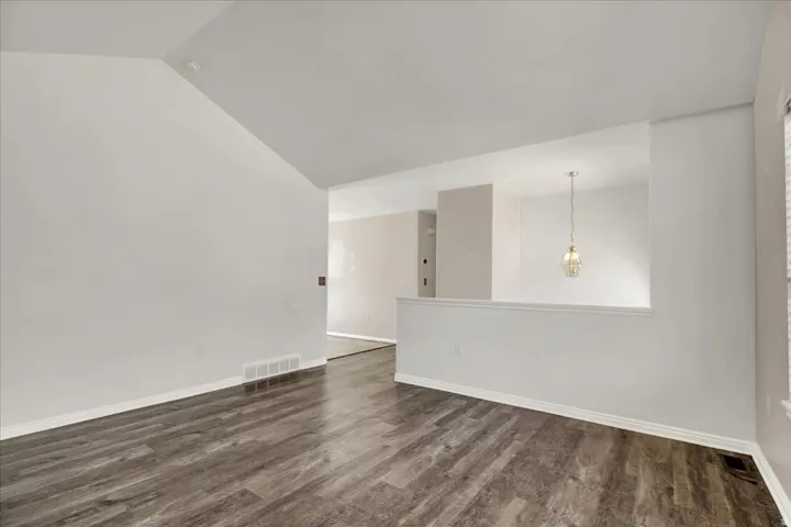 Interior living space featuring wood-finish flooring, vaulted ceiling, and a prominent half-wall architectural element