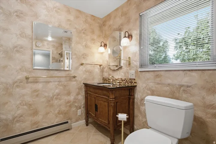 Bathroom featuring a vanity with a dark wood cabinet, a mosaic tile backsplash, and a polished countertop