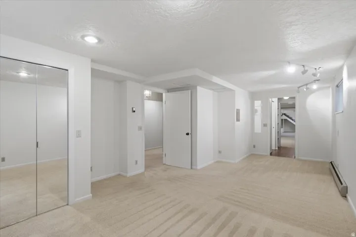 Spacious room featuring neutral carpeting and white walls