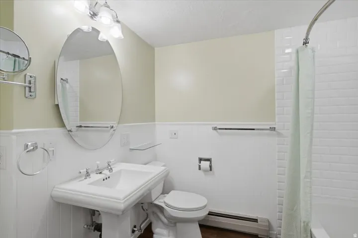 Bathroom featuring a white pedestal sink with chrome fixtures, an oval mirror, and a three-light vanity fixture