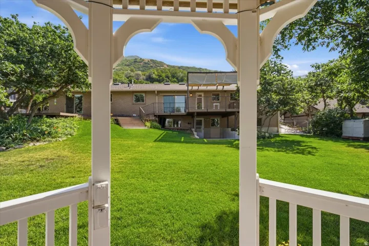 Expansive backyard featuring a manicured lawn, mature trees, and mountainous terrain in the background
