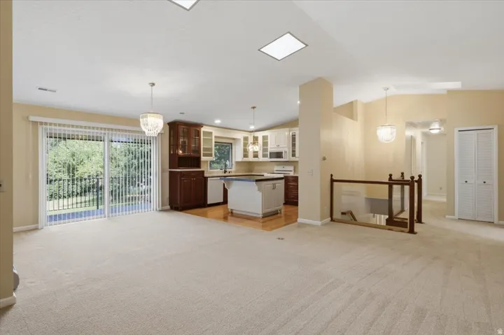Open-concept living area with neutral carpeting, recessed lighting, and a skylight