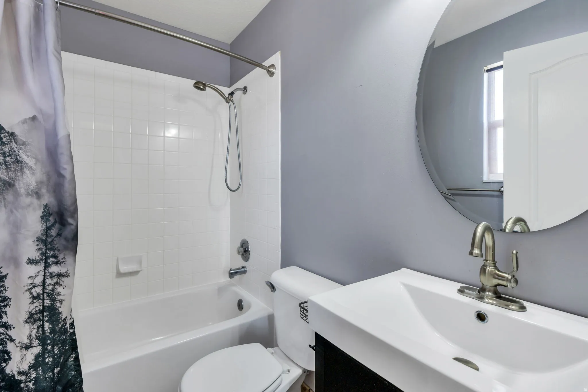 Bathroom featuring a tub/shower combination with white subway tile surround, a built-in toilet, and a vanity with a white integrated sink and brushed nickel faucet