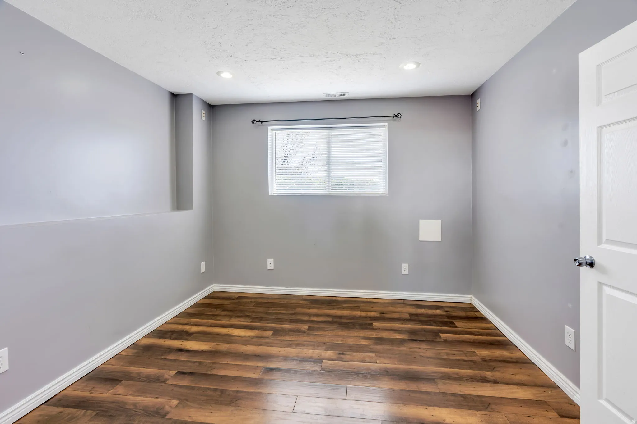 Room featuring wood-finish flooring, recessed lighting, and a window with blinds