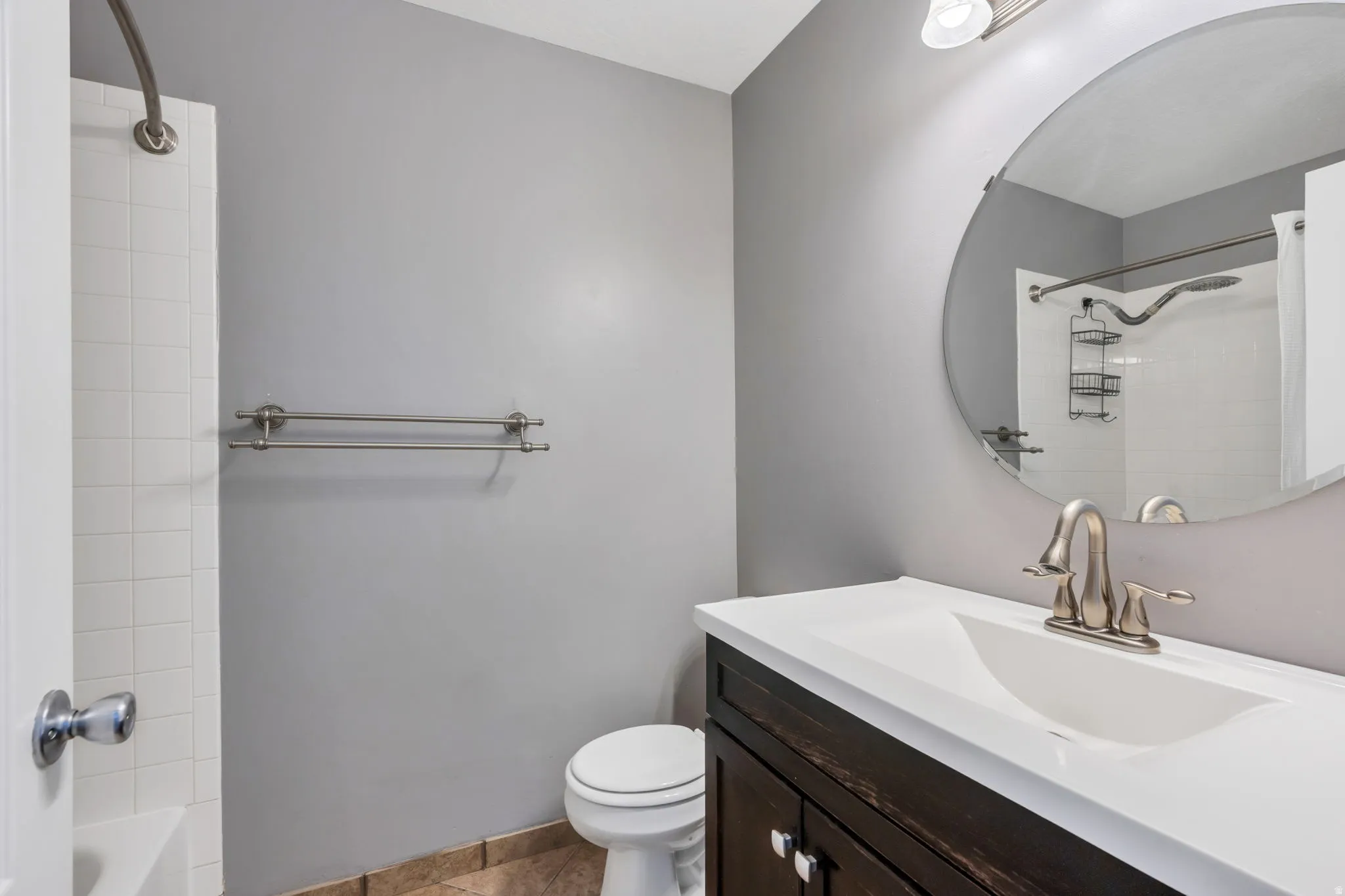 Bathroom vanity featuring a white countertop with an integrated sink, brushed nickel faucet, and dark wood-finish cabinetry