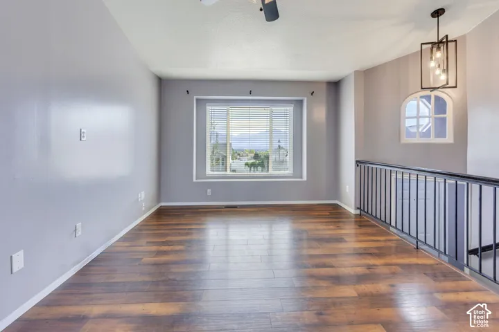 Spacious room featuring wood-finish flooring, a large window with blinds, and a distinctive arched window