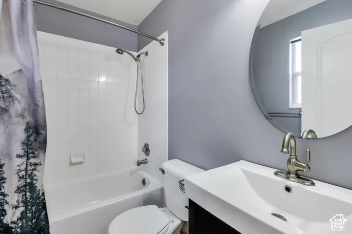 Bathroom featuring a tub/shower combination with white subway tile surround, a built-in toilet, and a vanity with a white integrated sink and brushed nickel faucet
