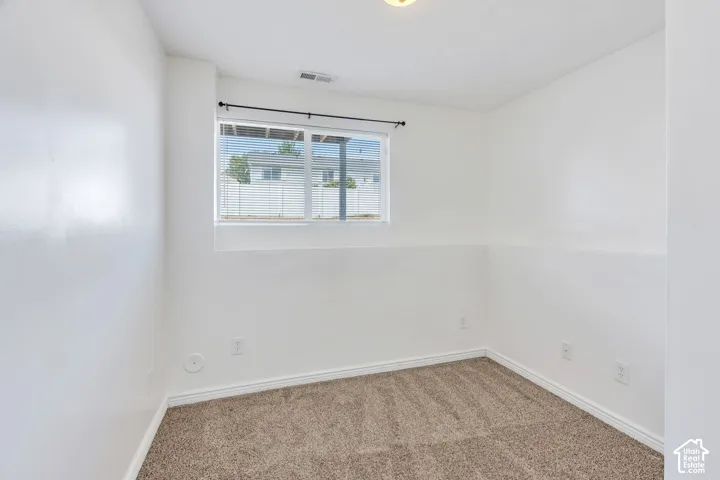 Bright room featuring a window with horizontal blinds, neutral-toned carpet, white walls, and white trim