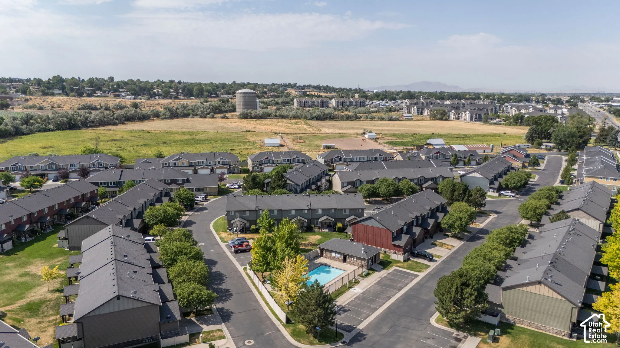 Aerial perspective of a multi-unit residential development featuring a central swimming pool and surrounding green spaces