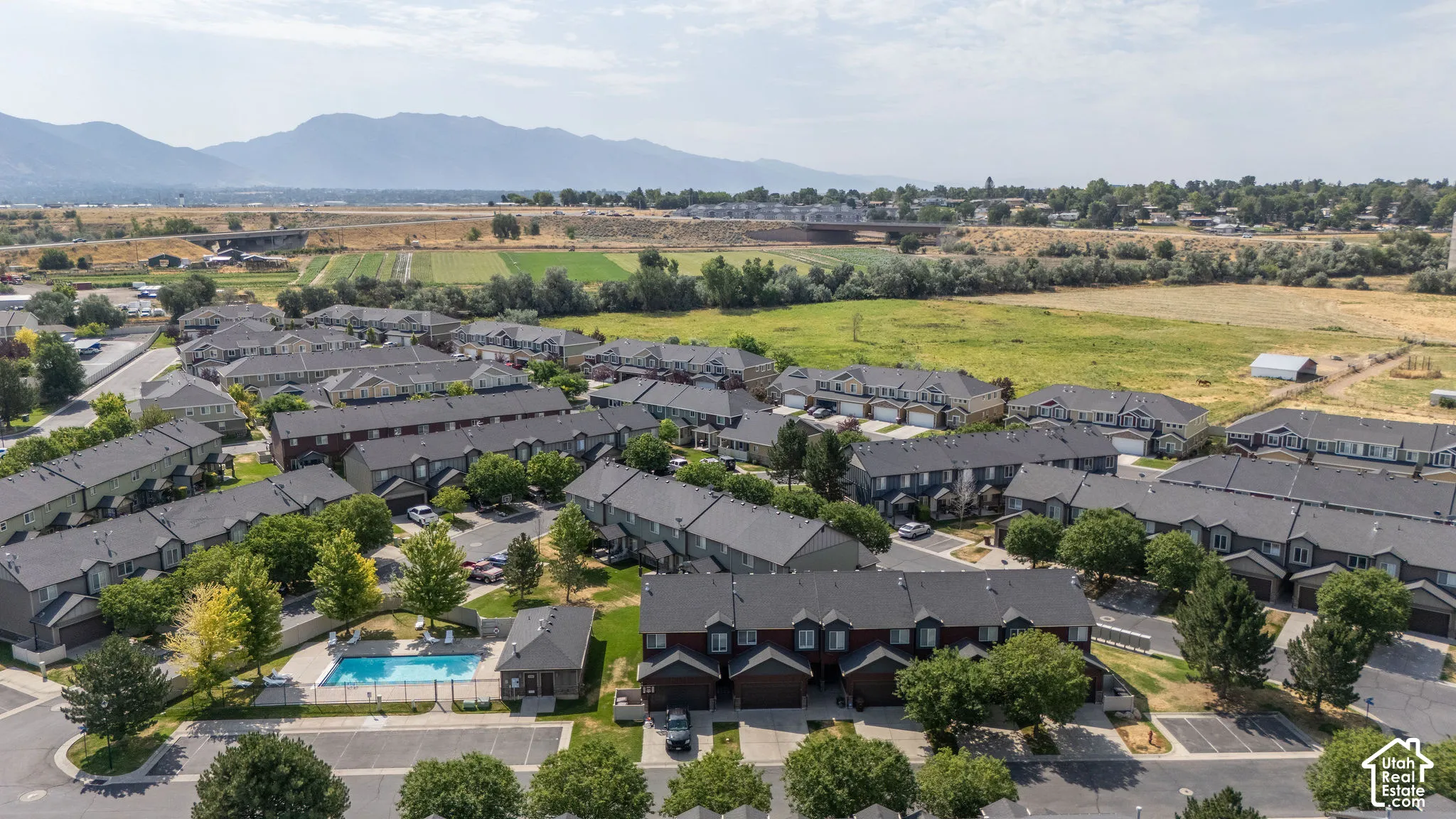 Aerial perspective of a multi-unit residential community featuring uniform townhome-style buildings with dark roofs