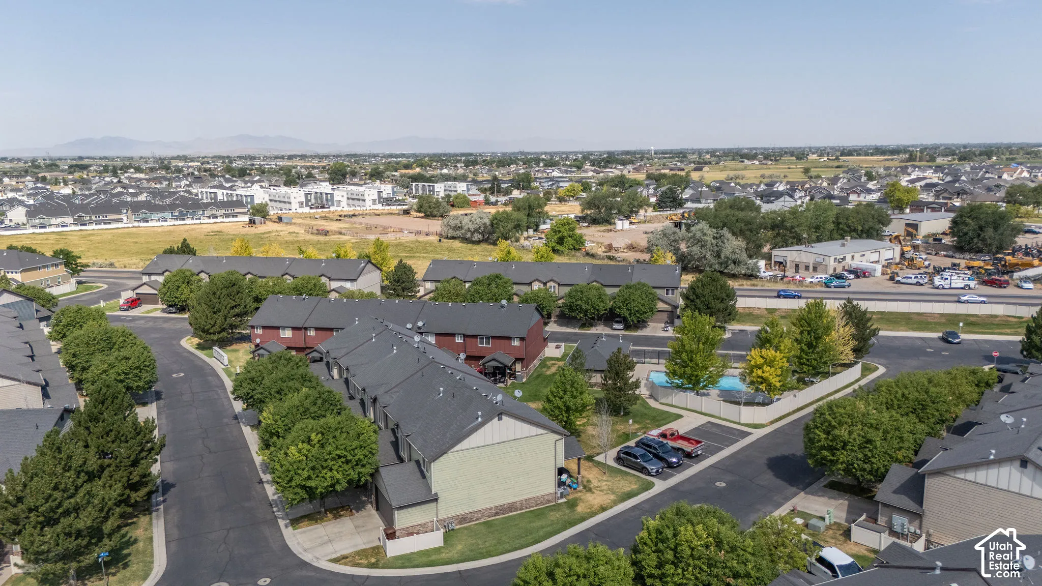 Aerial perspective featuring multiple residential structures with dark shingled roofs and mature trees