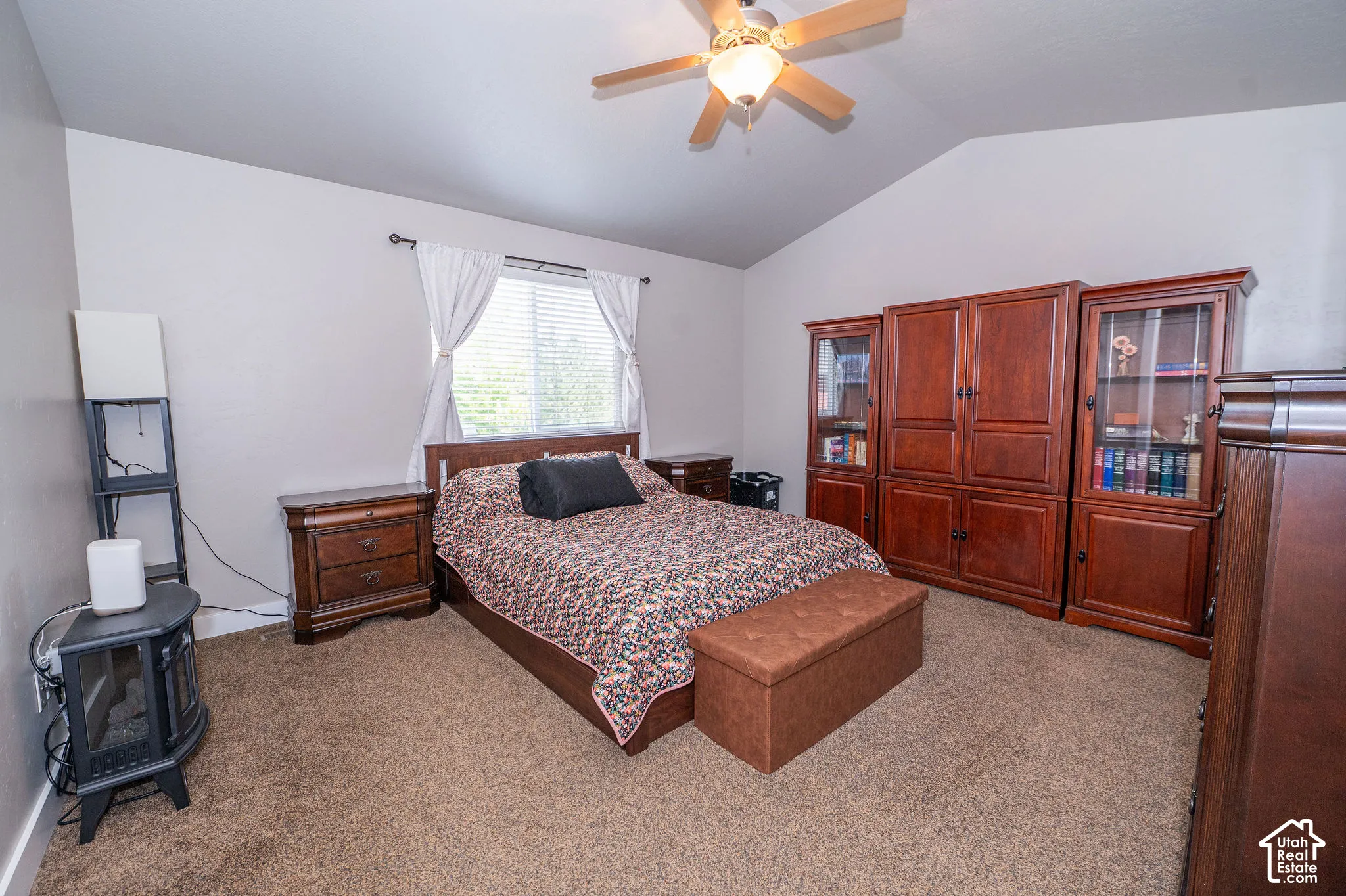 Carpeted room featuring a vaulted ceiling with a ceiling fan light fixture