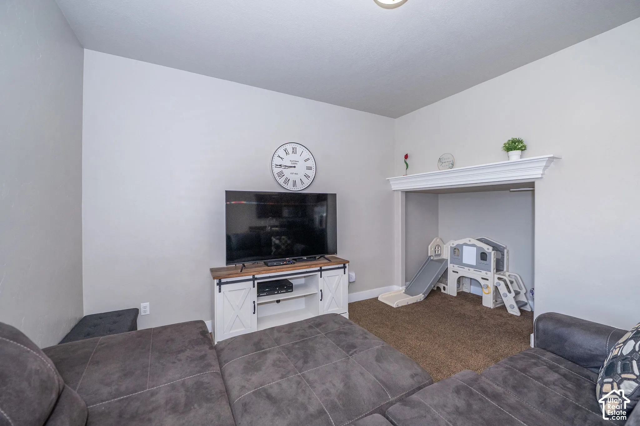 Recessed alcove with carpeted flooring and an ornate mantel, complemented by light gray wall paint and a light fixture