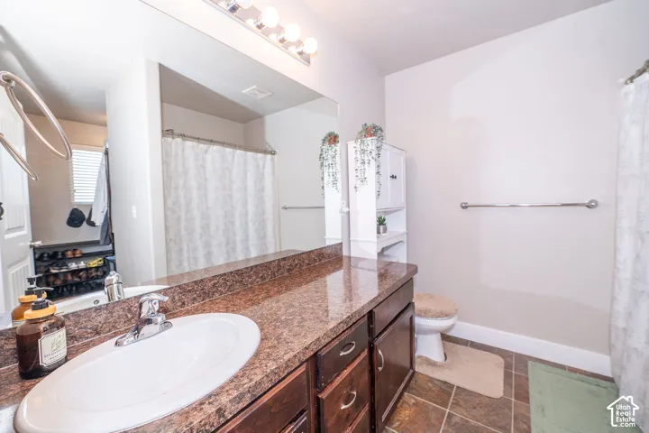 Bathroom featuring a vanity with dark wood-finish cabinetry, a white oval sink, and a speckled countertop