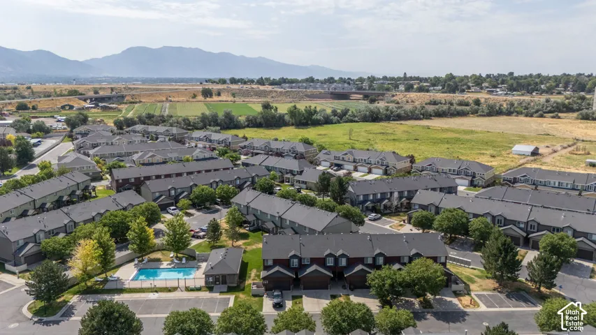 Aerial perspective of a multi-unit residential community featuring uniform townhome-style buildings with dark roofs