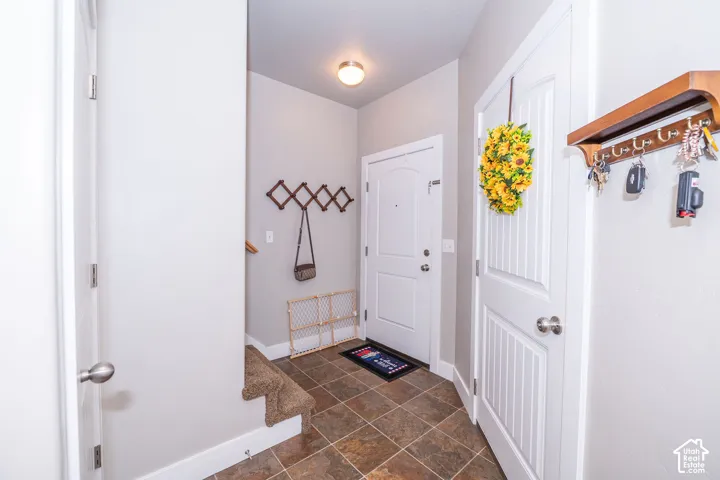 Entryway featuring brown tile flooring, white baseboards, and light gray walls
