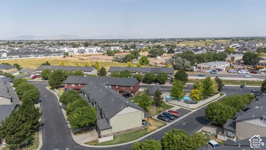 Aerial perspective featuring multiple residential structures with dark shingled roofs and mature trees
