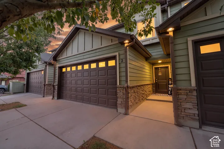 Exterior siding in a muted green, stone veneer accents, and a dark entry door