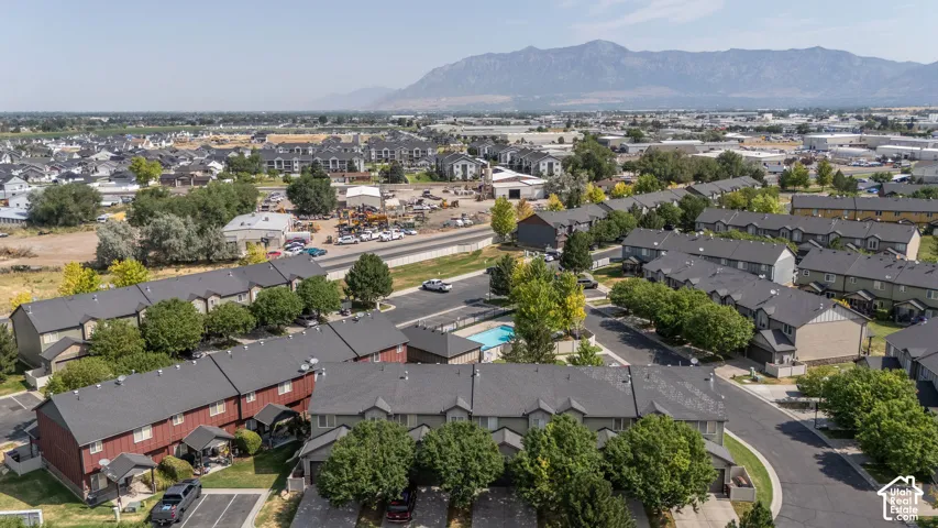 Aerial perspective showcasing a residential community with multi-story townhomes, dark shingle roofing, and mature perimeter trees