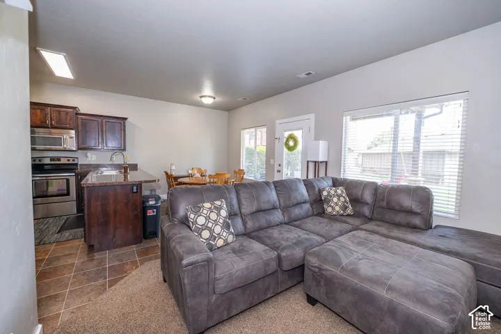Open-concept living area featuring a kitchen with dark wood-finish cabinetry, stainless steel appliances, and a granite-style countertop