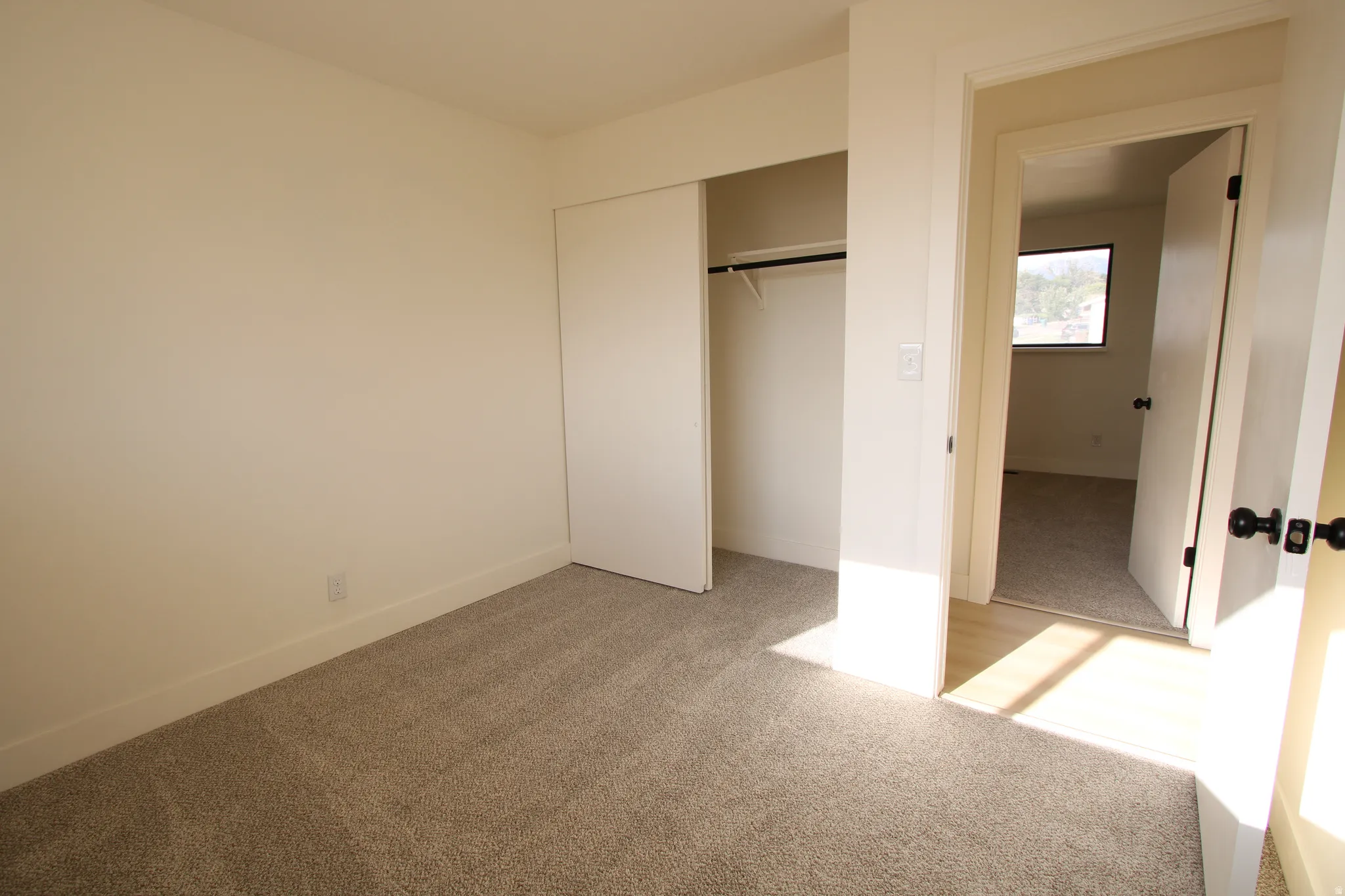 Room featuring neutral-toned carpeting, light-colored walls, and a bi-fold door closet with an interior hanging rod