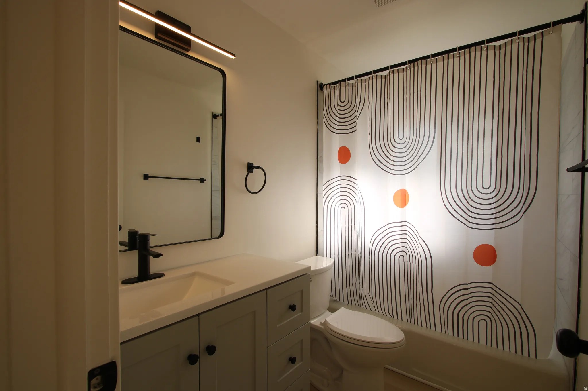 Bathroom vanity featuring a quartz-finish countertop with an integrated sink and a matte black faucet