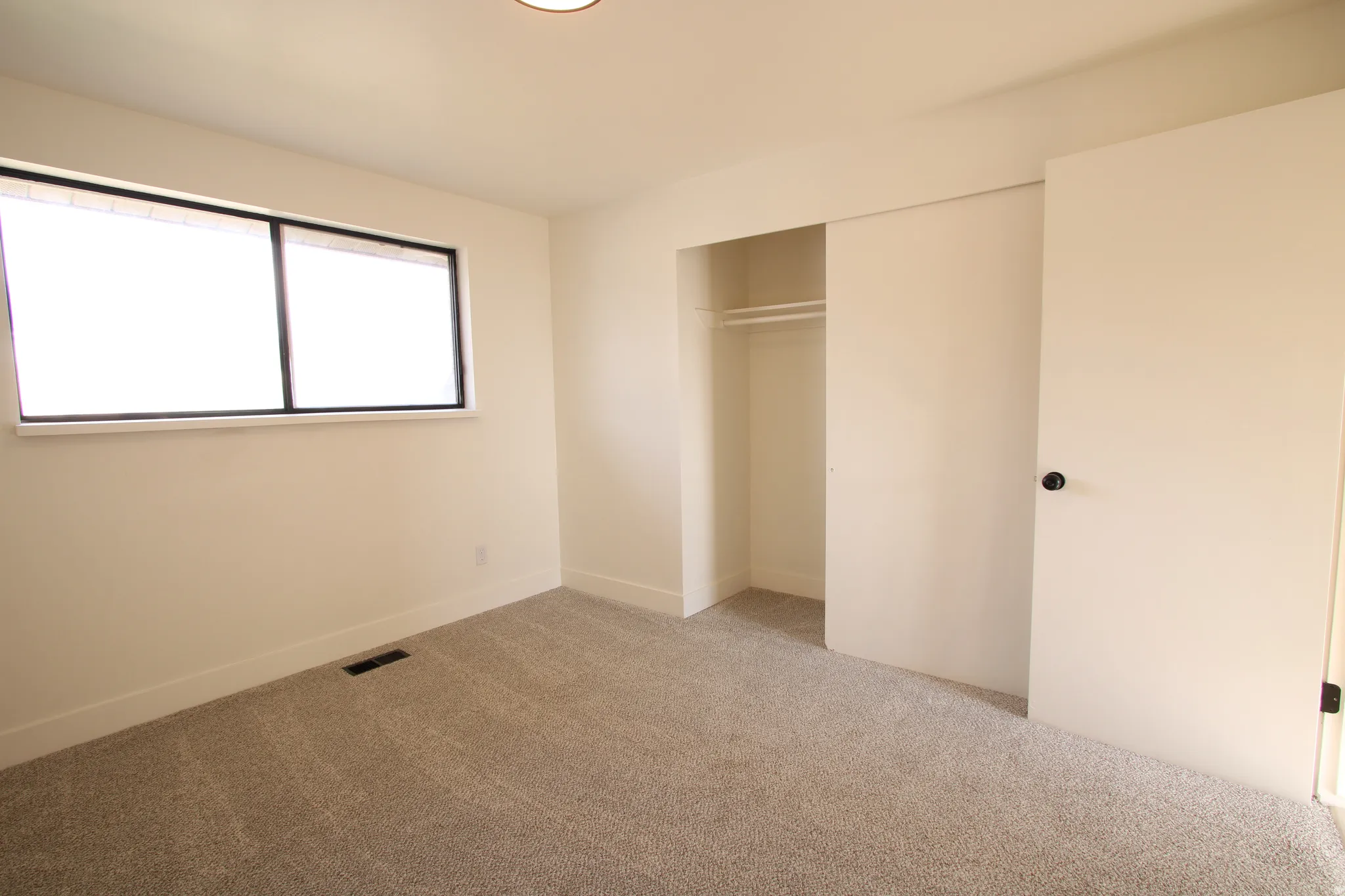 Carpeted room featuring a double-paned window with dark trim, a built-in closet with sliding doors, and recessed ceiling lighting