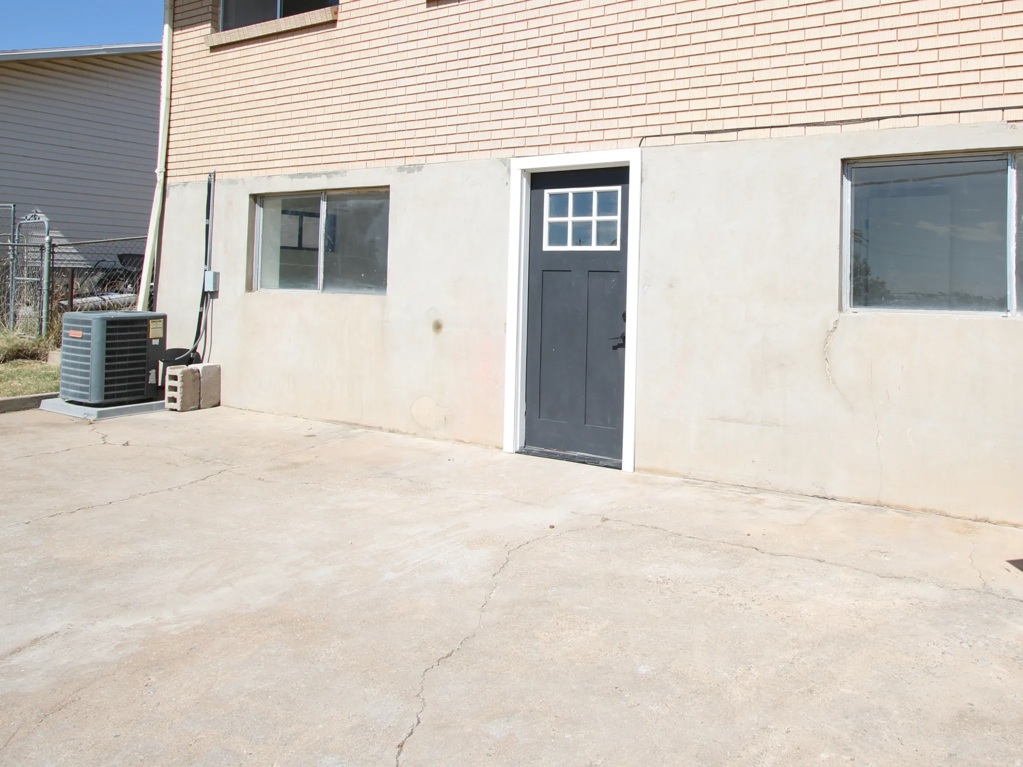 Exterior brick facade with a concrete foundation and a dark entry door