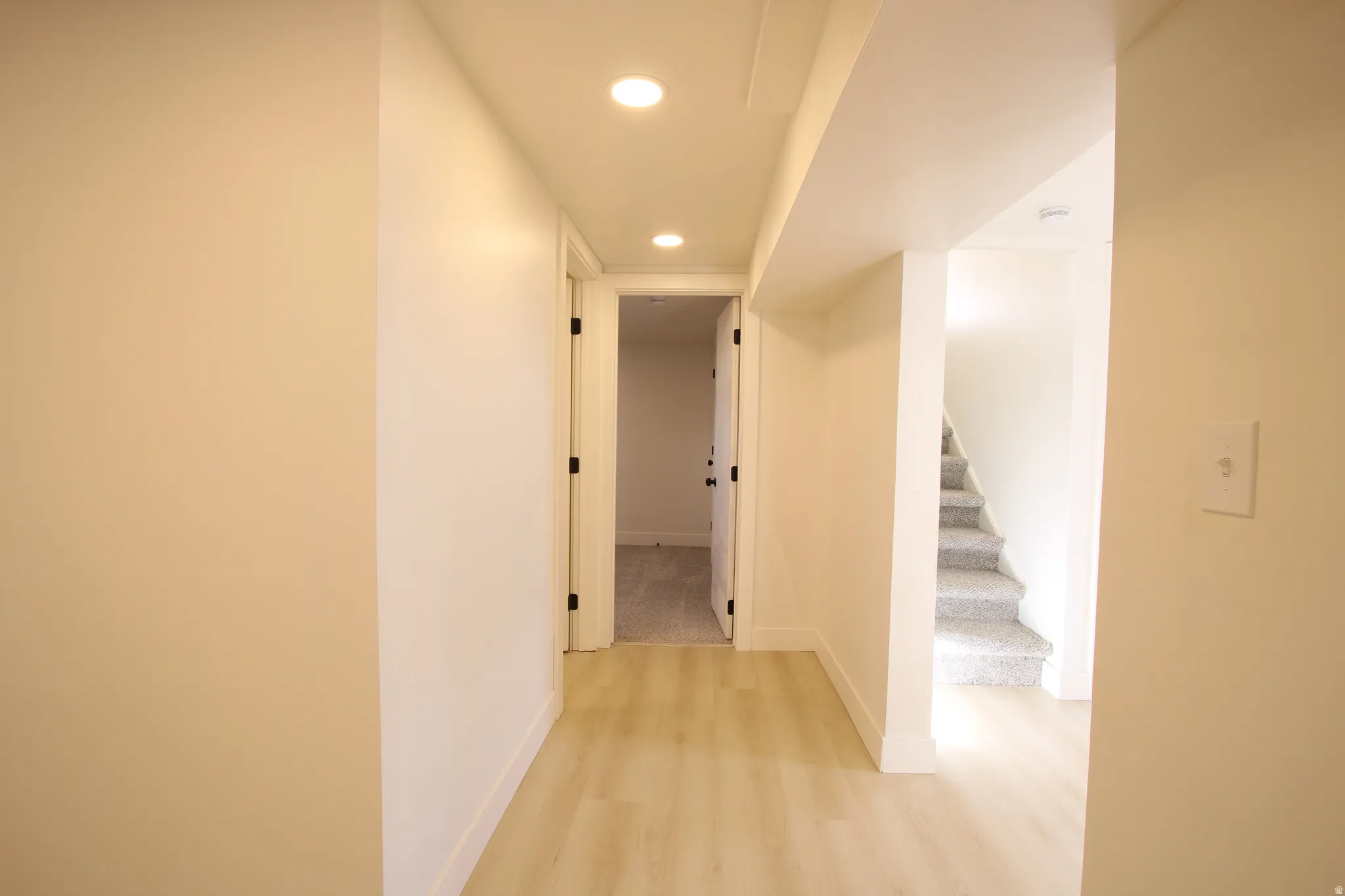 Hallway featuring wood-finish flooring, recessed lighting, and white trim