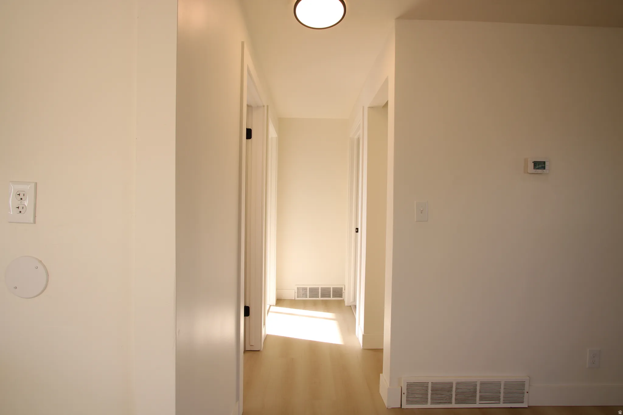 Hallway featuring light-toned wood-finish flooring, white walls, and recessed lighting