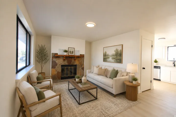 Stone-faced fireplace with a wood mantel, wide window with dark trim, recessed lighting, and wood-finish flooring