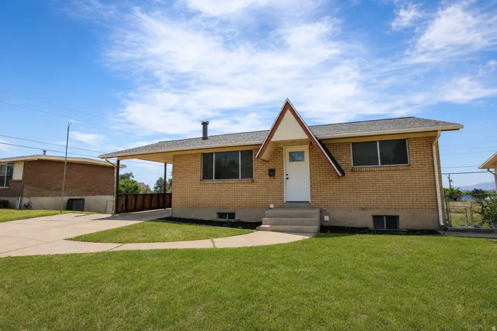 Brick exterior with a unique peaked entry overhang, featuring a covered carport and a concrete driveway