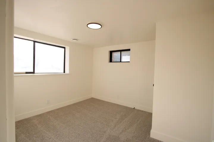 Clean interior space featuring light-colored walls and grey carpet flooring