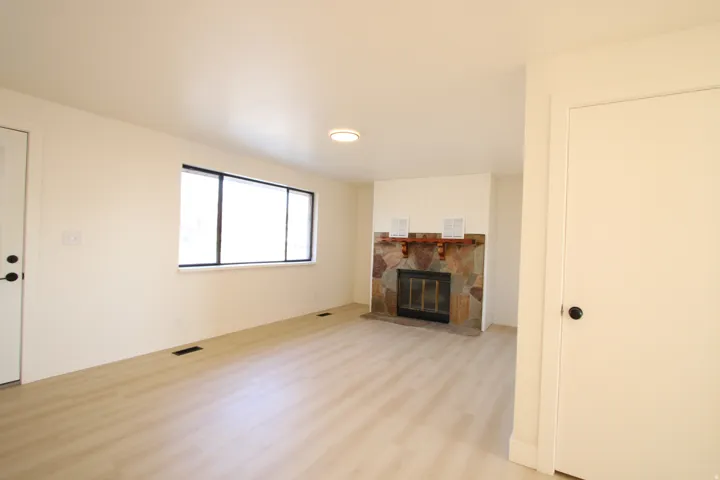 Recessed fireplace featuring a natural stone surround and wood mantel